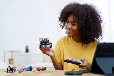 Mutlu neşeli Amerikalı - Afrikalı siyahi üniversite öğrencisi kadın robotik ve programlamayı kendi başına öğreniyor, kadın robot bir araya getiriyor.