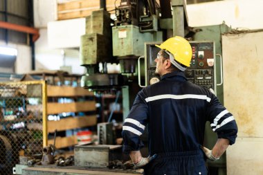 Beyaz ırktan profesyonel beyaz erkek teknisyen torna fabrikasında ağır iş makinesini çalıştırıyor. Güvenlik teknisyeni ve kask giysisi fabrikada bir makineyi kontrol ediyor..