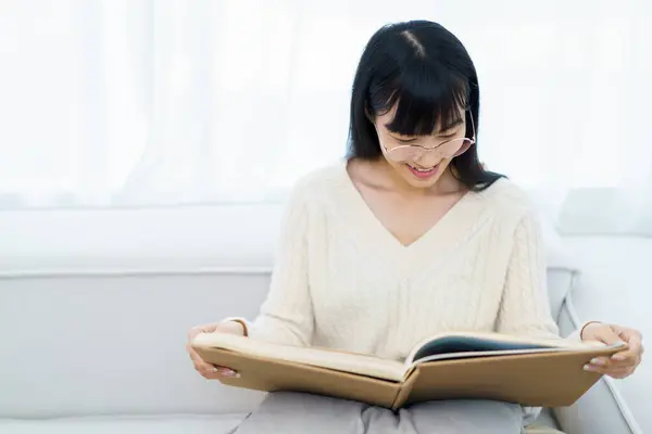 Szczęśliwa Radosna Azjatka Okularach Ocznych Siedząca Kanapie Salonie Czytająca Samotnie — Zdjęcie stockowe