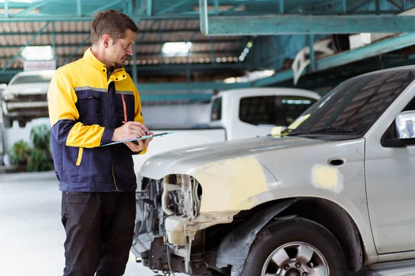 ガレージで損傷した車を検査する上級プロの自動車技術者 車の機械技術者や技術者は 固定する前に車の周りを検査してチェックする — ストック写真