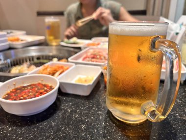 Bira fıçısını bardaktaki bira bardağıyla yakın çekim yapın. Yakiniku Grille masasında..