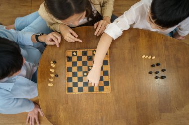 Mutlu Asyalı güzel aile hafta sonu oturma odasında kalıp satranç oynuyor Asyalı insanlar birlikte satranç oynuyorlar..