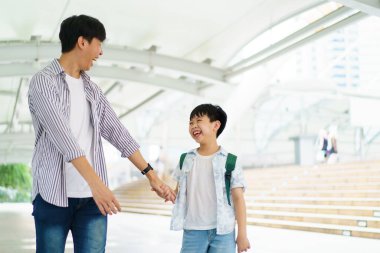 Baba oğlunu okula götürüyor, okula yürürken çocuk elini tutan bir adam..