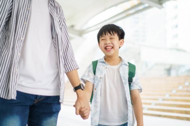 Baba oğlunu okula götürüyor, okula yürürken çocuk elini tutan bir adam..