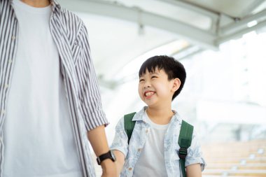 Baba oğlunu okula götürüyor, okula yürürken çocuk elini tutan bir adam..