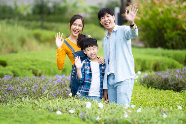 Happy Asian family father mother and son posing for a photography in flowers and botanical garden. Portrait of cheerful Asian family doing a weekend activity together in flower - botanical garden.
