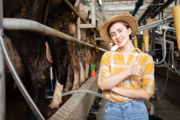 Happy cheerful caucasian white female farmer making arms crossed and smiling to camera while standing in cow dairy farm. Female vet or veterinarian inspecting a livestock cows in farm.