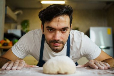 Neşeli İtalyan şef mutfaktaki ahşap masada taze pizza hamuru yapıyor..