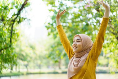 Mutlu mutlu Asyalı güzel bayan müslüman egzersiz yapıyor ve parka yakın bir yerde fotokopi aletiyle esniyor. Modern Müslüman kadın yaşam tarzları ve çeşitlilik kavramı.