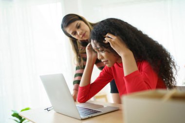 Mutsuz genç bir kadın. Defterin önünde kötü bir yüz ifadesi sergiliyor. Arkadaşı da onu cesaretlendirmeye geliyor..