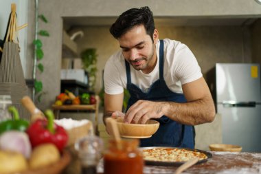 Profesyonel İtalyan şef evde peynirli Hawaii pizzası pişiriyor. İtalyan şef fırında pişirmeden önce mozzarella peyniri, domates sosu, sebze ve et ile Hawaii pizzasını tepeledi..
