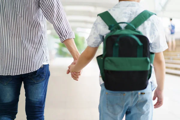 Babası seyahatten döndükten sonra neşeli Asyalı çocuk babasına koşuyor ya da gökyüzü tren istasyonunda. Mutlu Asyalı aile baba ve oğul kavramı.