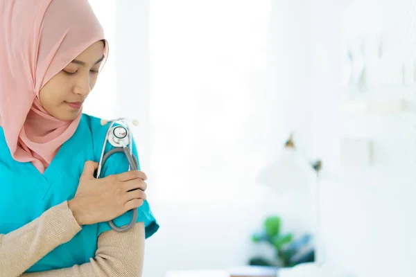 Asian female muslim doctor holding a doctor or medical stethoscope and crossed arms close up with copyspace. An expertise or occupation in modern muslim people concept.