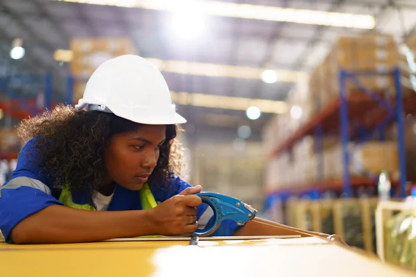 Professional American - African black woman warehouse worker working in the factory or warehouse, black female warehouse employee packing and showing parcel package.