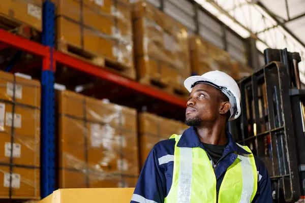 Portrait of smart good looking African - American Black warehouse staff - worker working in warehouse, handsome African warehouse worker in safety helmet and vest working.