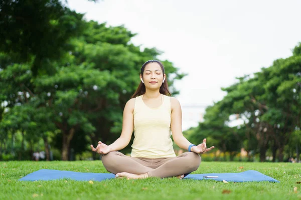 Güzel, zeki ve yakışıklı Asyalı yetişkin bir kadın güzel bir günde yoga ya da vücut ağırlığı egzersizi yapıyor ve çim tarlasında yoga yapıyor. Refah ve sağlıklı yaşam tarzı kavramı..