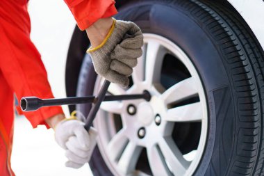 Hidrolik kriko kullanan teknisyen ya da tamirci arka tekerleği değiştirmek için arabayı kaldırır..