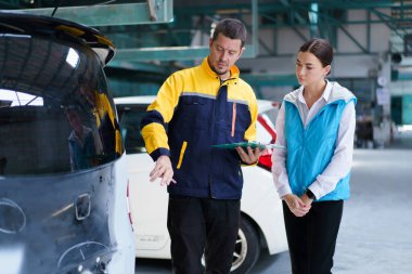 Sigorta poliçesi ya da teknisyen, kadın müşteriyle garajdaki kaza aracı hakkında konuşmak için konuşuyor..