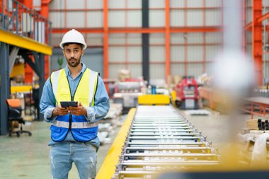 Metal levha fabrikasındaki ağır bir makineyi inceleyen Asyalı profesyonel sanayi mühendisi..