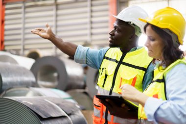 Makine mühendisi ekibi fabrikada birlikte çalışıyor. Mühendisler fabrikadaki metal makine sistemini inceliyor..