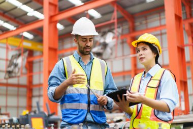 Metal levha fabrikasındaki ağır bir makineyi inceleyen Asyalı profesyonel sanayi mühendisi..