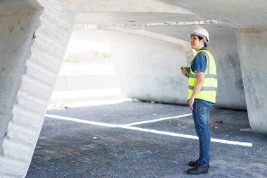 Ağır altyapı şantiyesinde çalışan profesyonel kıdemli Asyalı inşaat mühendisi, inşaat mühendisi - bölüm inşaat köprüsünü denetleyen ustabaşı.