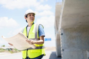 Asyalı profesyonel - köprünün planlarını ve inşaat planını inceleyen kıdemli cilt mühendisi veya inşaat mühendisi, köprü inşaatında çalışan inşaat mühendisi.