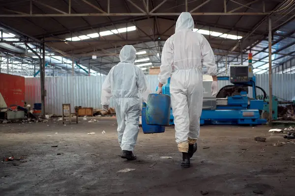 Team of scientist wearing a chemical protection suit and high efficiency filter face mask working in the bio - chemical contaminated factory. Bio chemical scientists working in the hazardous area.