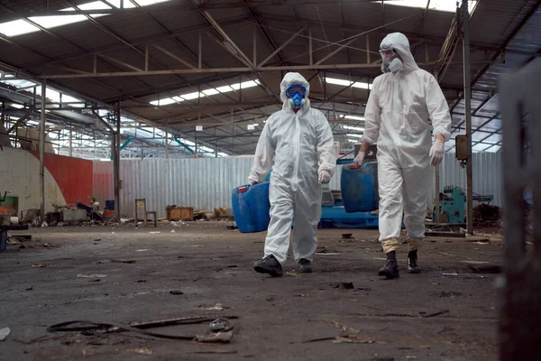 Team of scientist wearing a chemical protection suit and high efficiency filter face mask working in the bio - chemical contaminated factory. Bio chemical scientists working in the hazardous area.