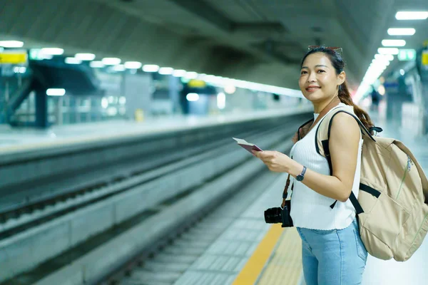 Tren istasyonunda tren bekleyen mutlu, güzel Asyalı kadın. Yalnız Asyalı kadın turist ya da gezgin tren istasyonunda duruyor..