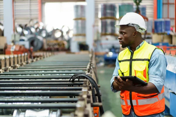 American - African worker inspecting machine in factory, machanical engineer working on machines in factory.