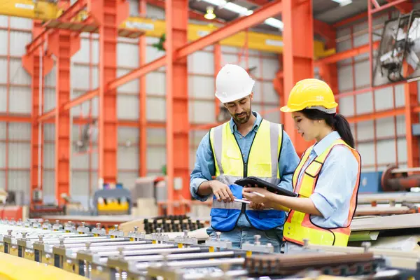 Metal levha fabrikasındaki ağır bir makineyi inceleyen Asyalı profesyonel sanayi mühendisi..