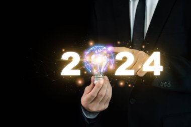 Güzel bir bağlantı çizgisi illüstrasyonuyla aydınlatılmış bir ampulü tutan bir iş adamı eli. Küreselleşme ve internet teknolojisindeki 2024 iş eğilimi. 2024 konseptinde eğilim.