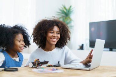 Afrikalı siyah etnik kökenli kardeş robot ve elektronik cihazları birleştirmeyi öğreniyor. Kadın kardeşine elektronik, robot ve programlamayı öğretiyor..