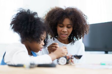 Afrikalı siyah etnik kökenli kardeş robot ve elektronik cihazları birleştirmeyi öğreniyor. Kadın kardeşine elektronik, robot ve programlamayı öğretiyor..