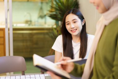 Mutlu Asyalı kadın lisansüstü öğrencisi birlikte bir proje tartışıp planlıyorlar. Çeşitli etnik kökenli insanların portresi.