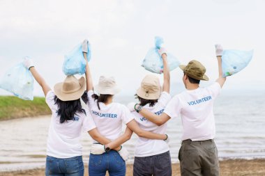 Bir grup Asyalı genç gönüllü parktaki plastik şişe çöplerini toplamaya ya da toplamaya yardım ediyor. Sürdürülebilirlik ve çevre koruma kavramı.