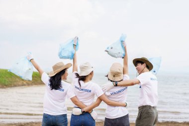 Bir grup Asyalı genç gönüllü parktaki plastik şişe çöplerini toplamaya ya da toplamaya yardım ediyor. Sürdürülebilirlik ve çevre koruma kavramı.