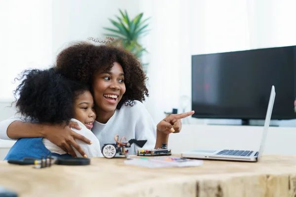 African black ethnicity sibling learn assembling robot and electronic devices. Woman teaching her sister about electronics, robot and programming.