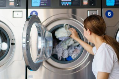 Mutlu Asyalı güzel kadın self servis çamaşır makinesi kullanıyor KIOSK ya da otomatik çamaşır makinesi satıcısı. Bir kadın markette kendi kendine çalışan bir çamaşır makinesiyle etkileşime geçiyor..