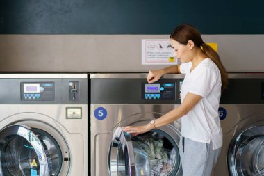 Mutlu Asyalı güzel kadın self servis çamaşır makinesi kullanıyor KIOSK ya da otomatik çamaşır makinesi satıcısı. Bir kadın markette kendi kendine çalışan bir çamaşır makinesiyle etkileşime geçiyor..
