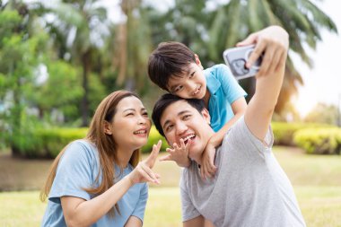 Mutlu Asyalı aile baba, anne ve küçük oğluyla birlikte parkta pikniğin keyfini çıkarın. Mutlu aile anları konsepti. Ebeveynleri ve çocukları parkta birlikte dinleniyorlar..