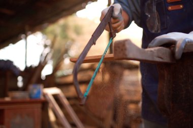 Asyalı marangoz testereyi kullandıktan sonra ahşap yüzeyi düzeltmek için ahşap zımparalama fırçası kullanıyor. Profesyonel marangoz bir ahşap fabrikasında çalışıyor..