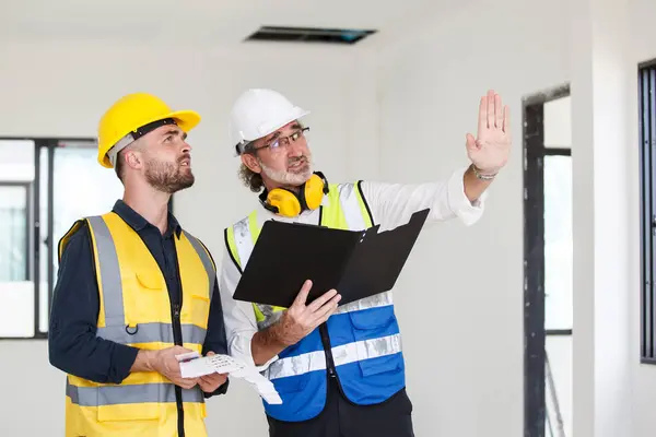 stock image Construction engineer and foreman having a discussion together at the construction site. Construction or civil engineers discuss for a building plan and architecture development.