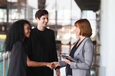Ofis koridorunda dikilen çeşitli etnik kökenden iş adamları, iş adamı ve iş kadını ofiste konuşuyor. İş ortaklığı ve takım çalışması kavramı.