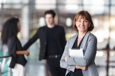 Ofis koridorunda dikilen çeşitli etnik kökenden iş adamları, iş adamı ve iş kadını ofiste konuşuyor. İş ortaklığı ve takım çalışması kavramı.