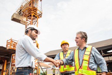 Mühendisler inşaat alanında aktif olarak çalışıyorlar, birbirleriyle detaylı tartışmalara giriyorlar. İnşaat projesinin çeşitli yönlerini işbirliği içinde inceliyorlar..
