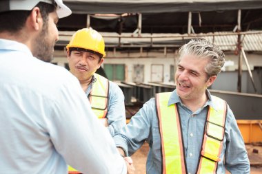 Mühendisler inşaat alanında aktif olarak çalışıyorlar, birbirleriyle detaylı tartışmalara giriyorlar. İnşaat projesinin çeşitli yönlerini işbirliği içinde inceliyorlar..