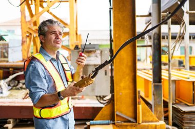 Kıdemli ustabaşı inşaat alanında ya da fabrikada teftiş yapıyor. Tehlikeli yerlerde dikkatsizce çalışıyor. Kaskı olmadan inşaat alanında çalışan dikkatsiz bir işçi..