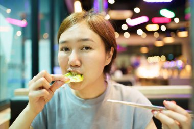 Mutlu Asyalı güzel kadın Kore restoranındaki ocakta ızgara yapıp geleneksel Kore barbeküsü yemekten hoşlanıyor. Asyalı kadın fırında domuz eti ve biftek pişiriyor..